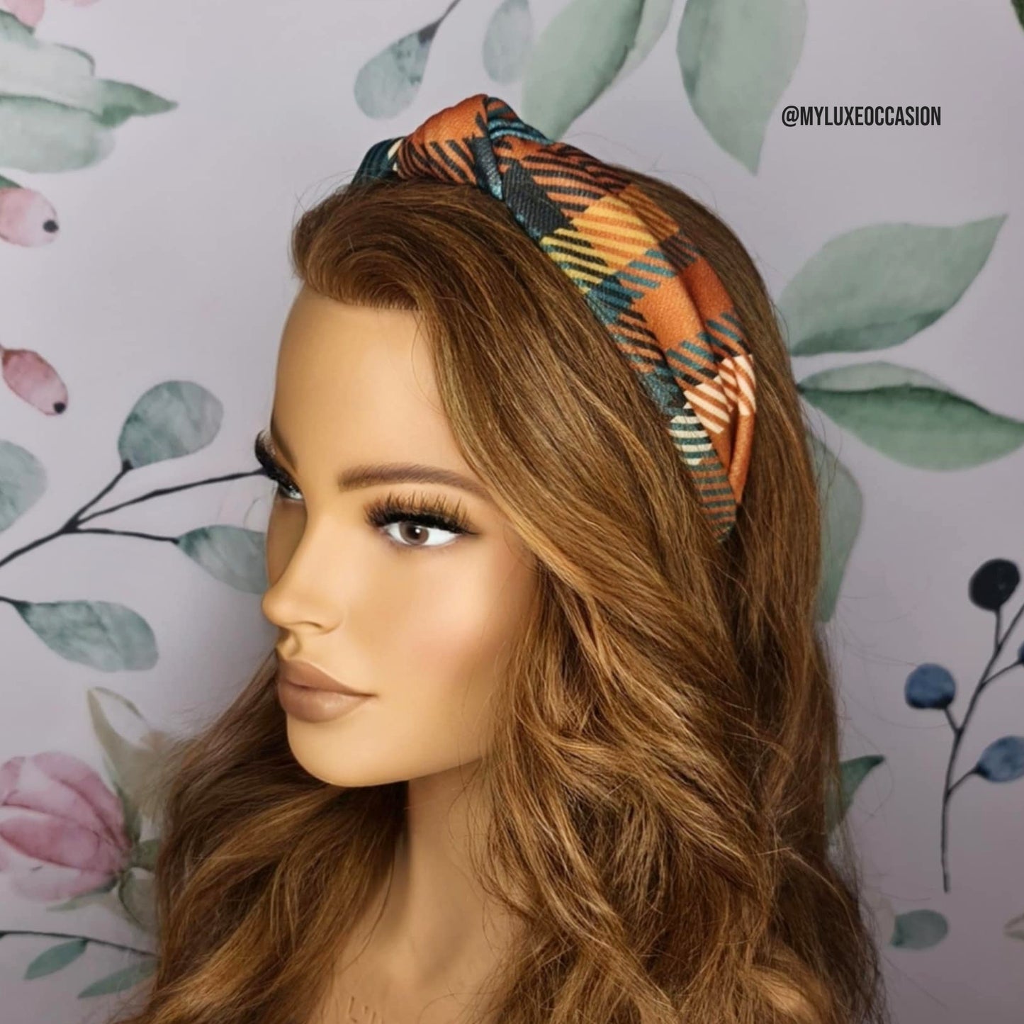 Mannequin head with a tartan headband against a floral background