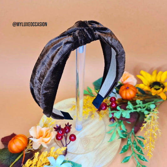 Brown velvet headband on a decorative stand with flowers and pumpkins.