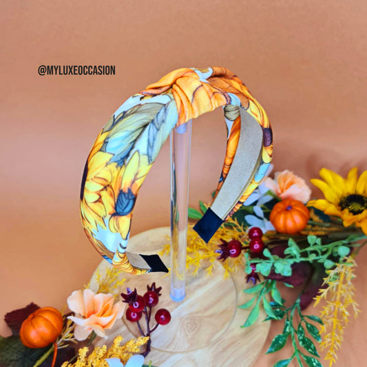 Colorful floral headband on a decorative stand with pumpkins and flowers.