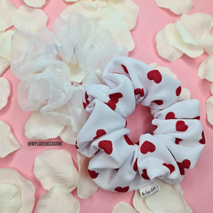 luxury heart print fabric scrunchie and white organza hair scrunchie on pink background with rose petals